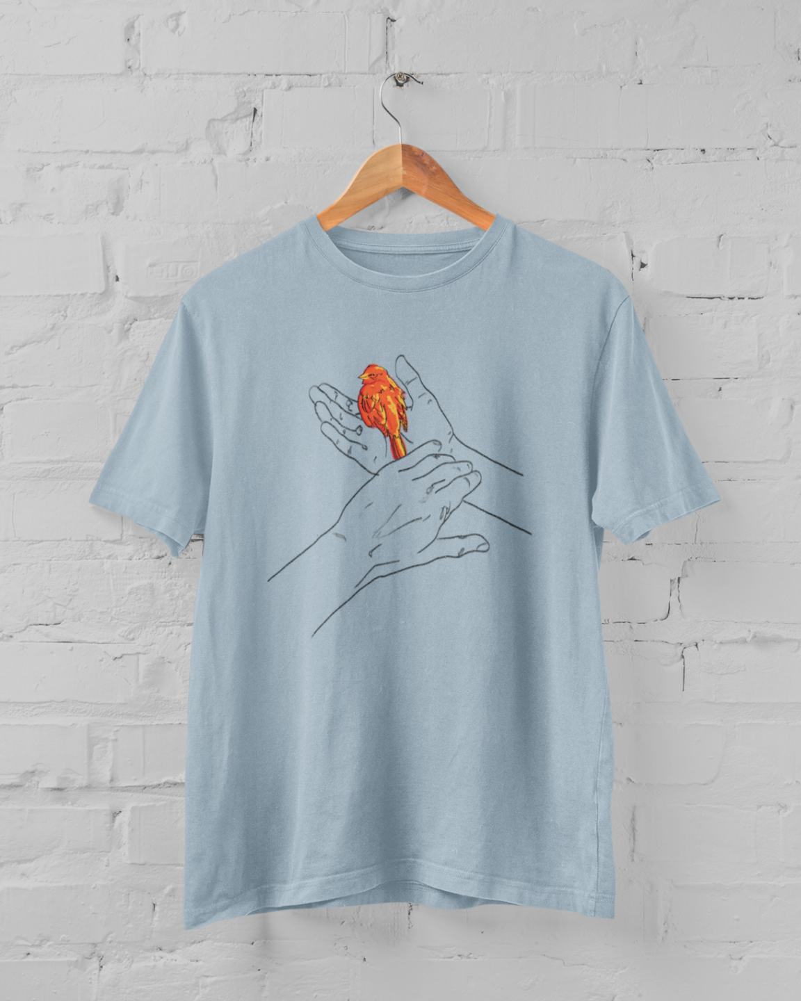 a light blue t shirt with grasp sparrows tail design on a hanger over a white brick backround
