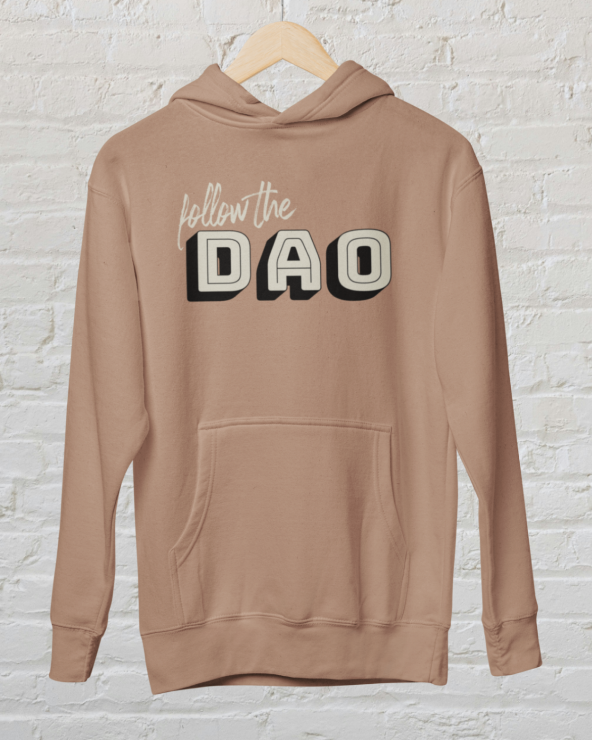  a caramel latte hoodie with follow the dao design over a white brick backround