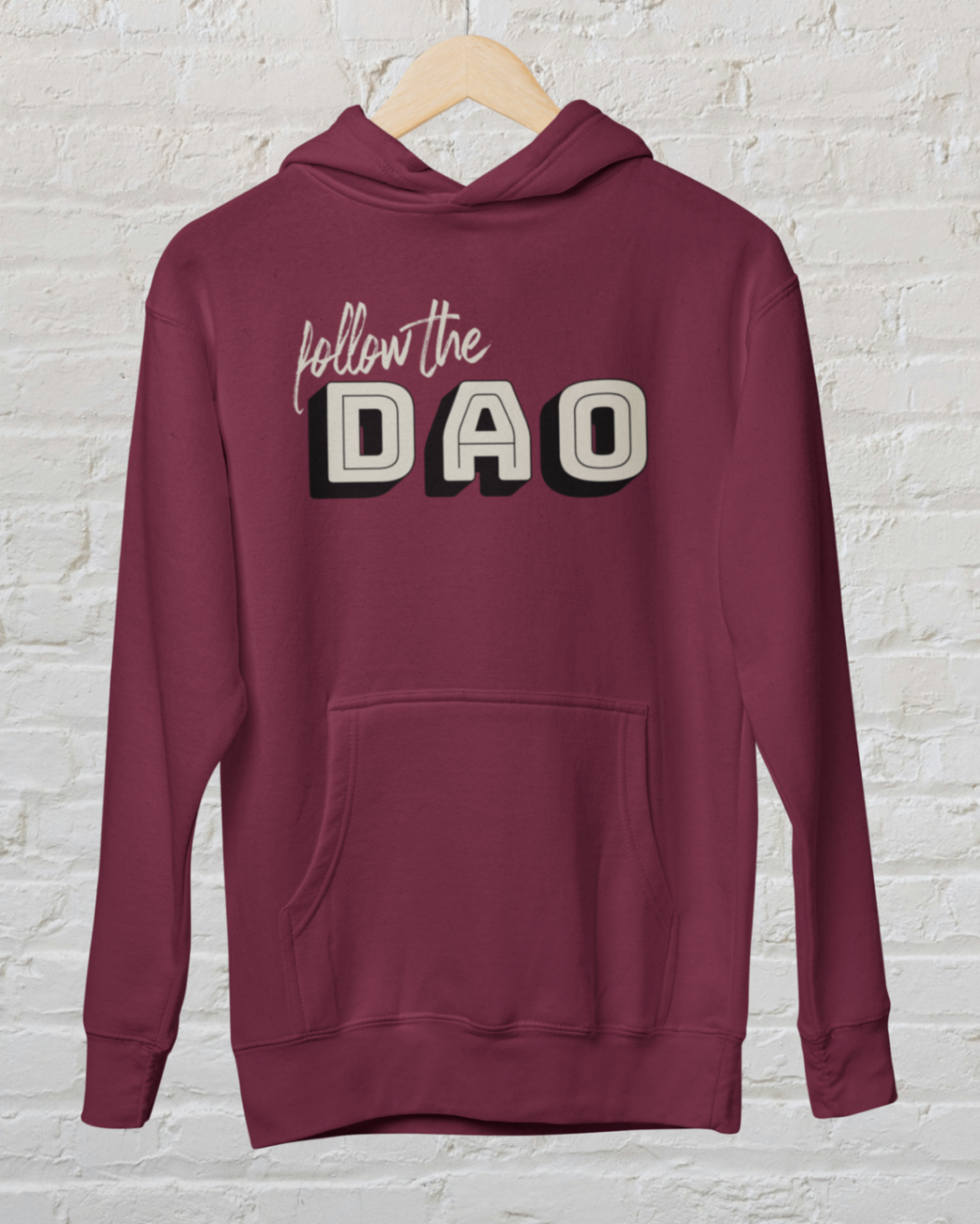 a Burgundy hoodie with follow the dao design over a white brick backround