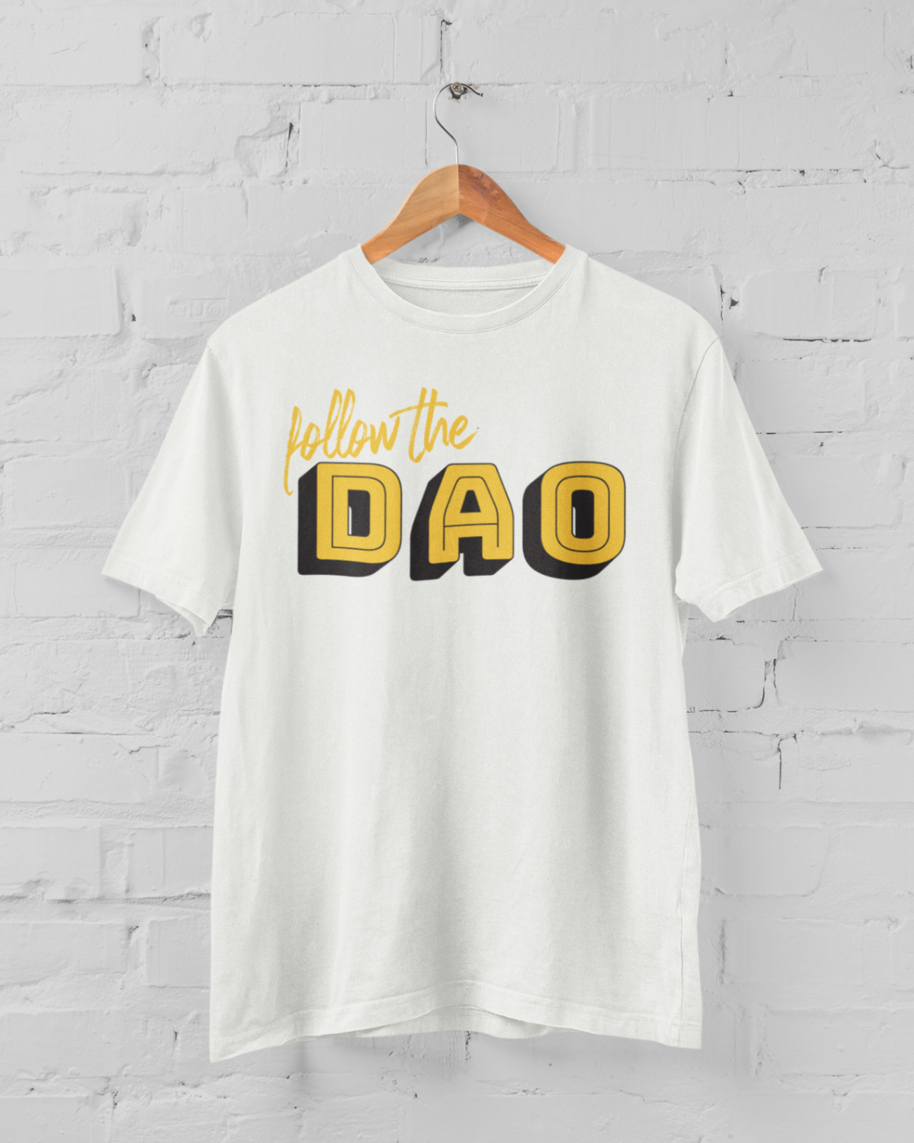 a white tshirt with black and yellow follow the Dao design on a hangar in front of a white brick backround