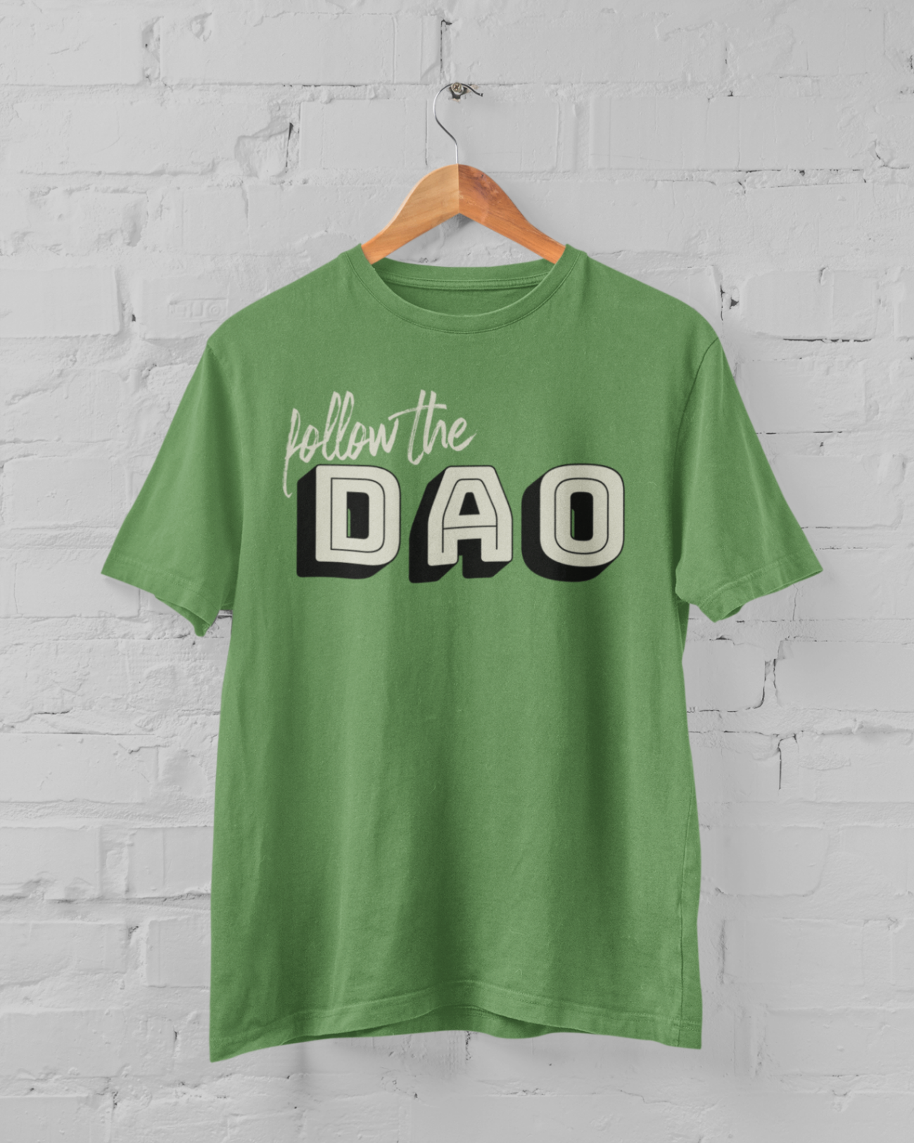  a leaf coloured t shirt with the follow the dao design on a hangar in front of a white brick backround