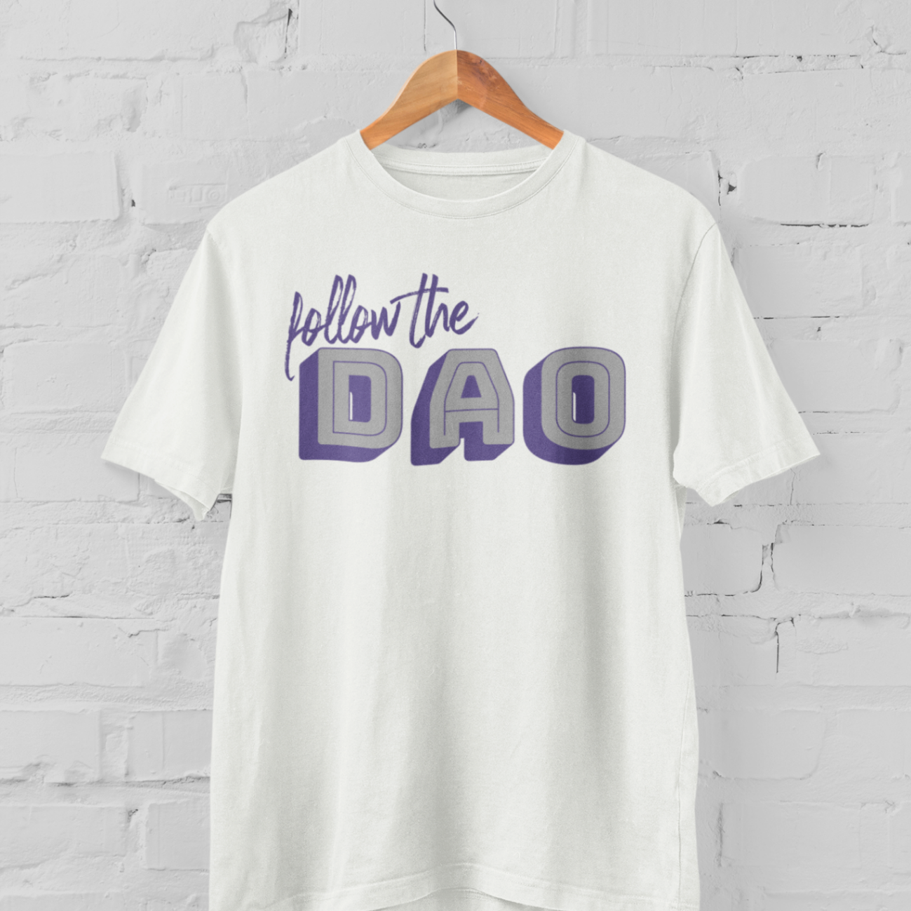 a white tshirt with purple and grey follow the Dao design on a hangar in front of a white brick backround