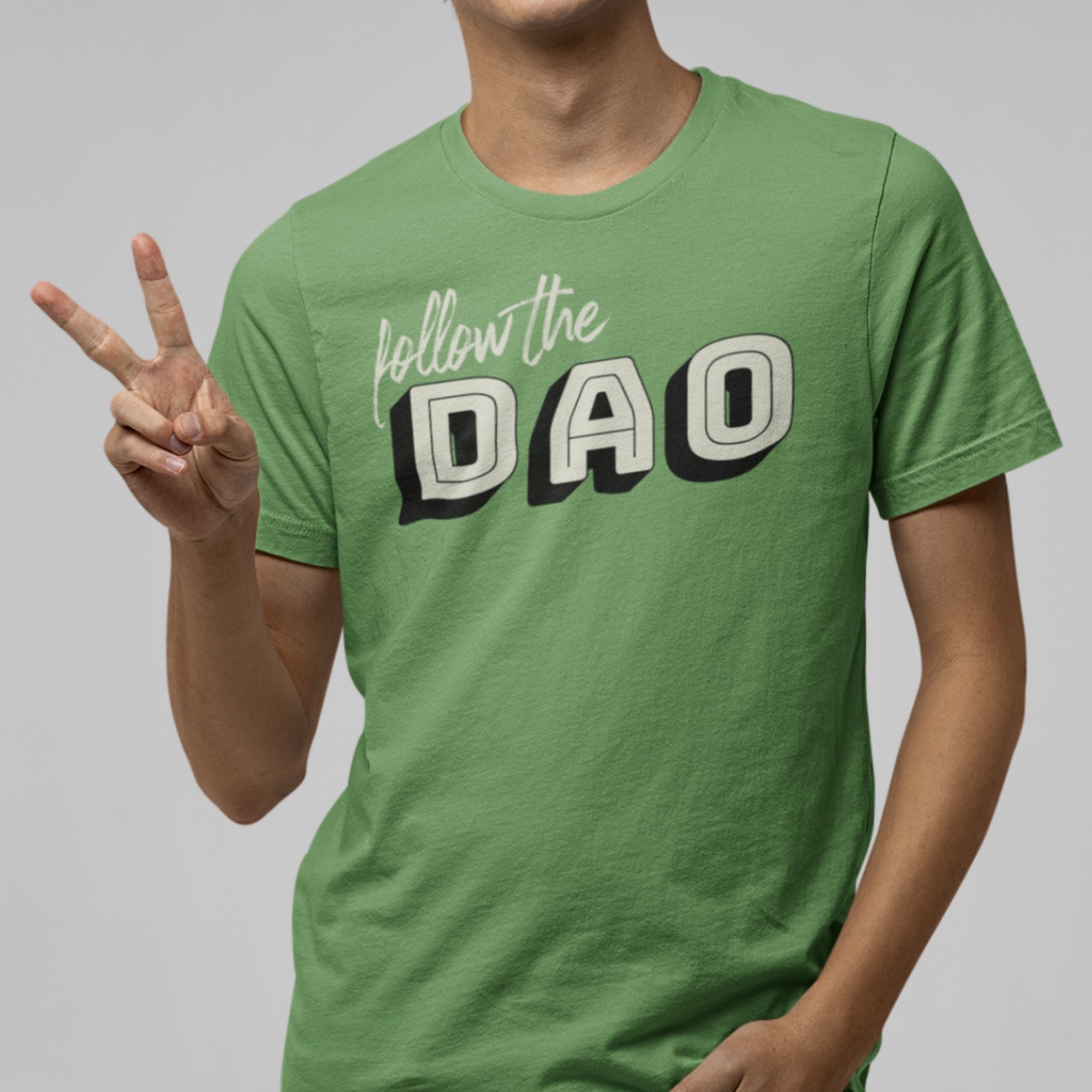 smiling man making the peace sign wearing a leaf coloured t shirt with follow the dao design