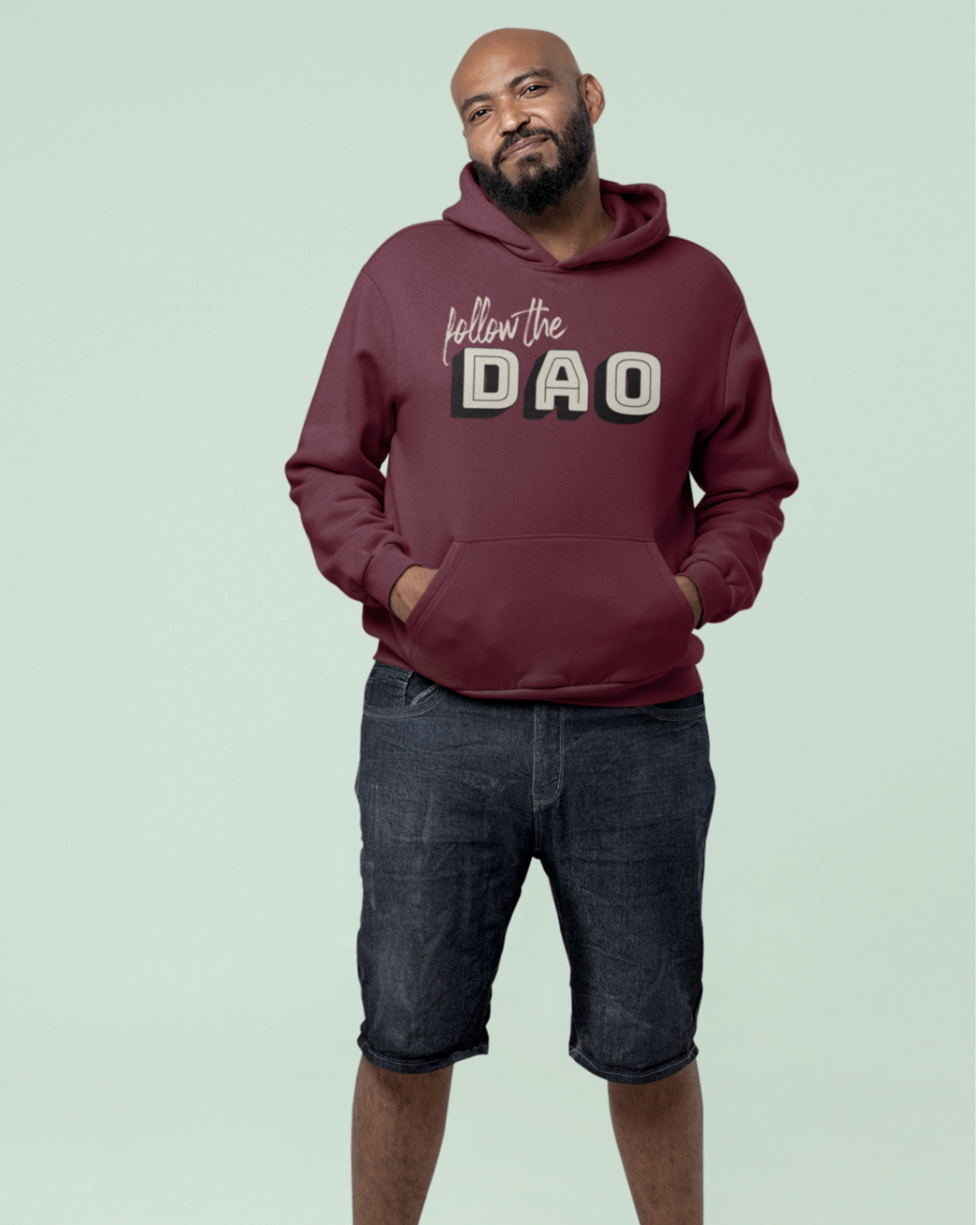 A relaxed model wearing a Burgundy hoodie with the follow the dao lettering design on front