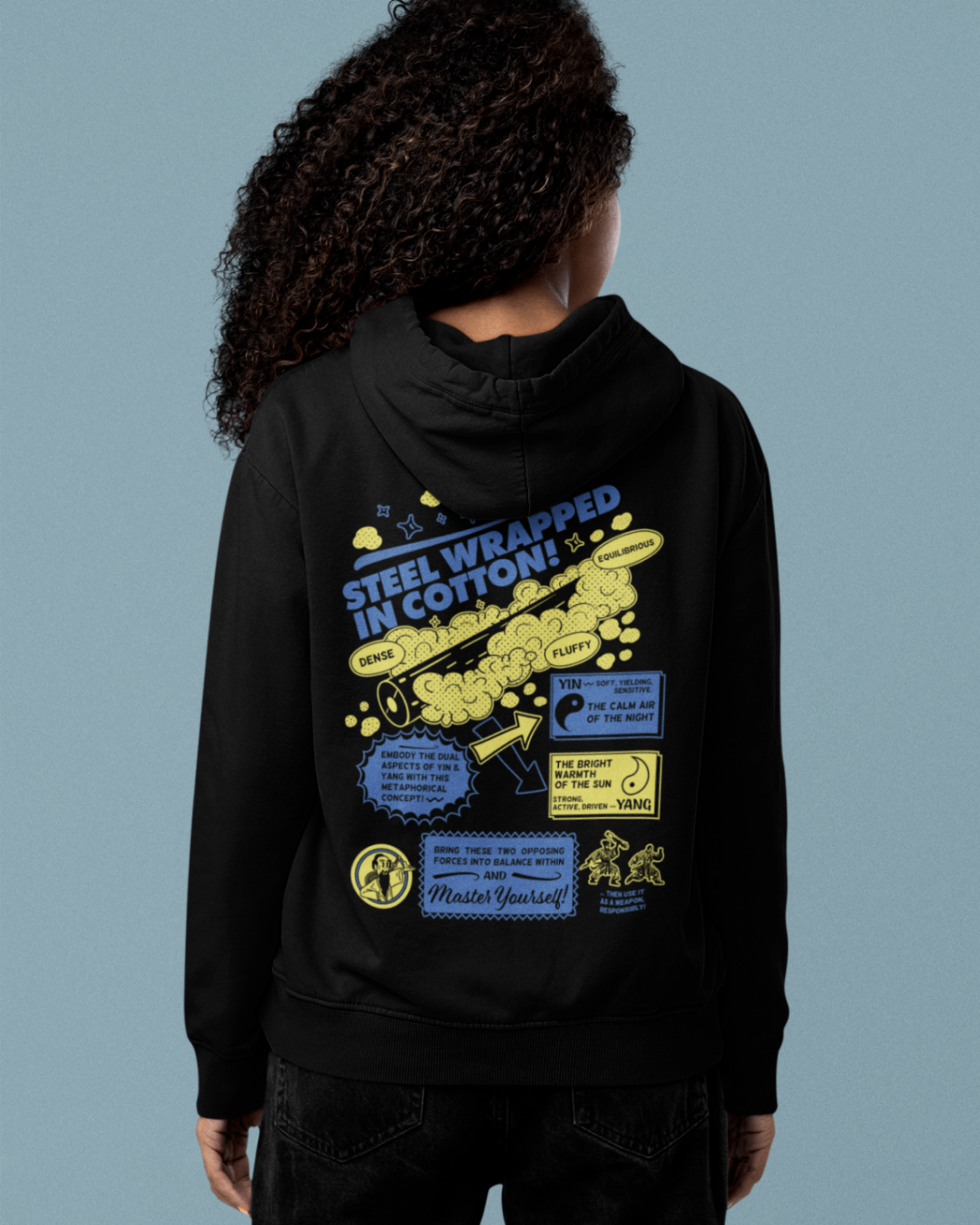 back view of a female model wearing a black zip up hoodie with steel wrapped in cotton design in yellow and navy text 