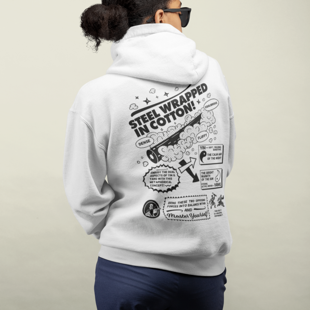  back view of a cool female model wearing a white zip up hoodie with steel wrapped in cotton design in all black text 