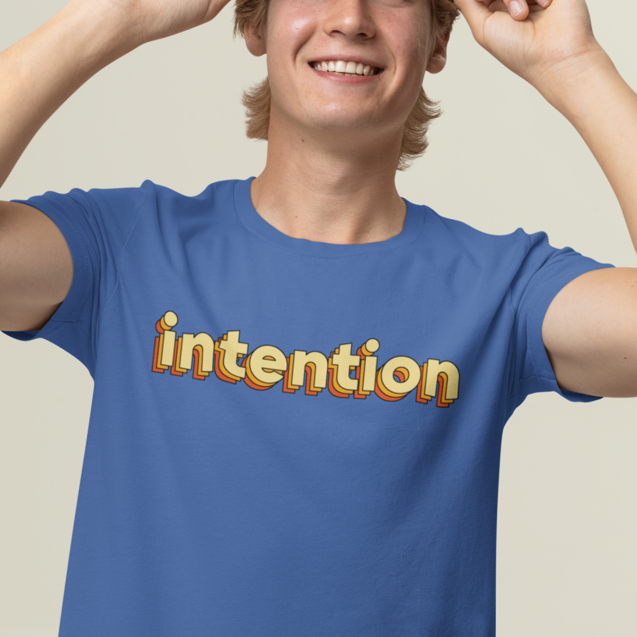 a smiling male model wearing a royal blue t shirt with intention written in 3 D lettering