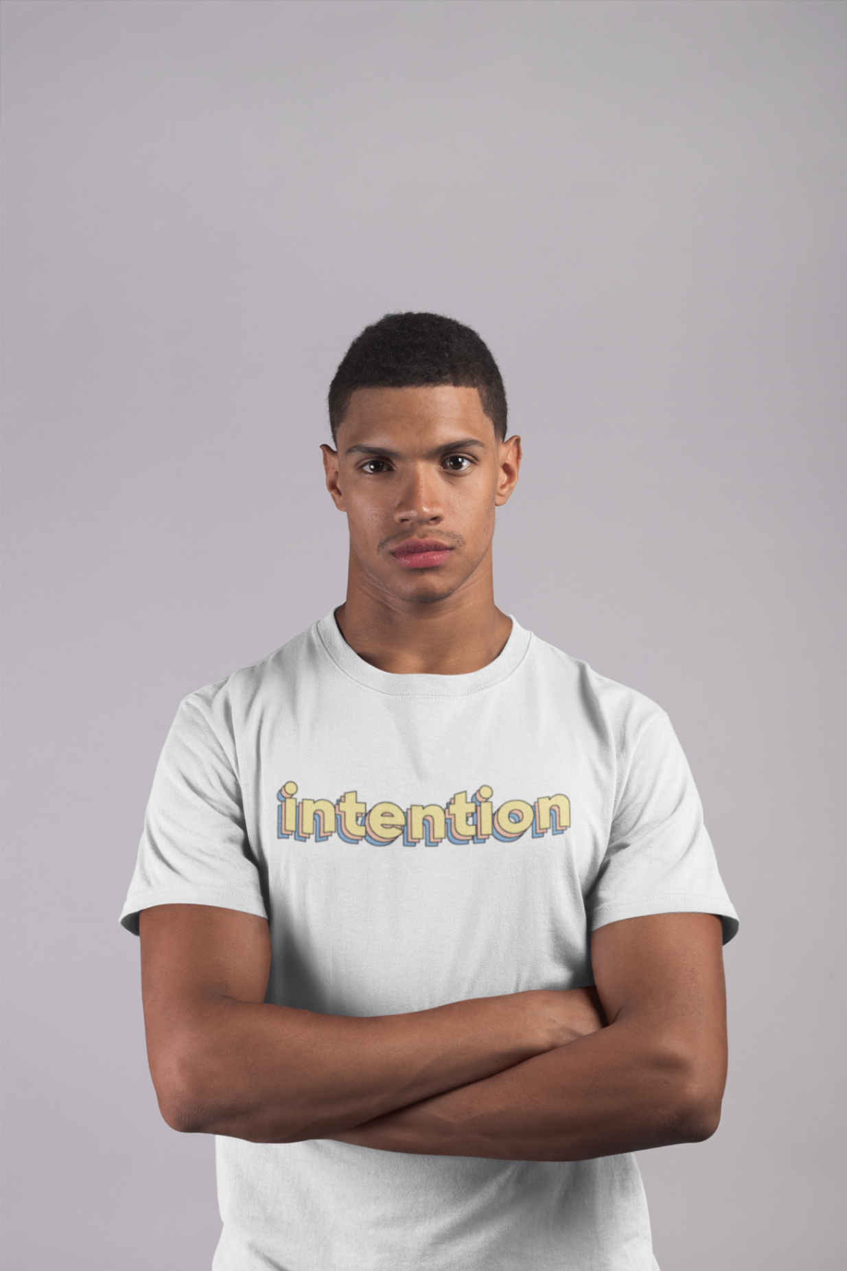 a serious male model wearing a white t shirt with intention written in 3 D lettering