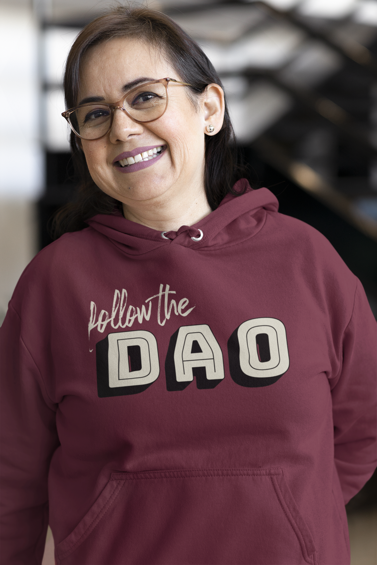 a smiling lady wearing burgundy hoodie with blocky follow the dao design on front