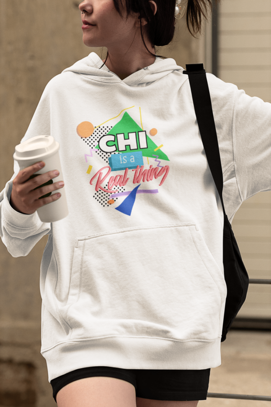 stylish woman wearing a white chi is a real thing hoodie with coffee cup crossing the street