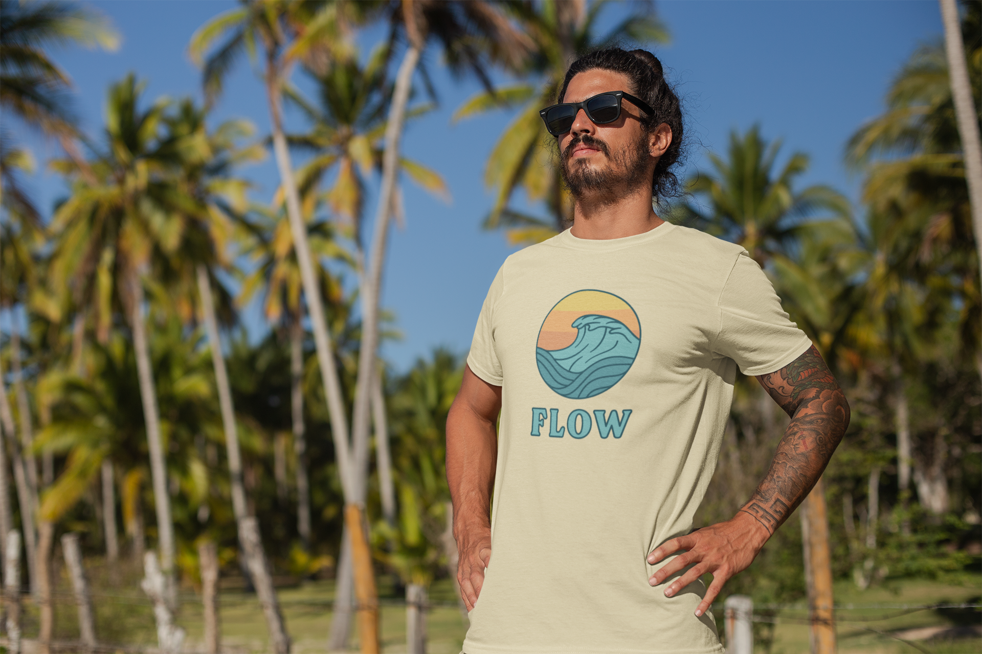 cool man in sunglasses wearing a cream tshirt with flow design, standing in nature looking into the distance
